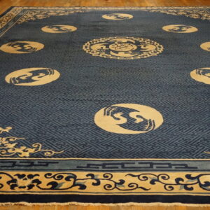 Dark blue rug with a fretwork background and cream medallions featuring stylized bird designs on wood flooring.