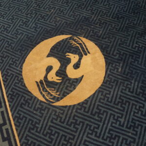 Gold stylized birds overlay a dark blue geometric key pattern field bordered by scrolls and meanders.