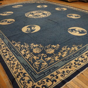 Blue and tan patterned rug with circular medallions and floral borders displayed on a warm-toned wood floor.