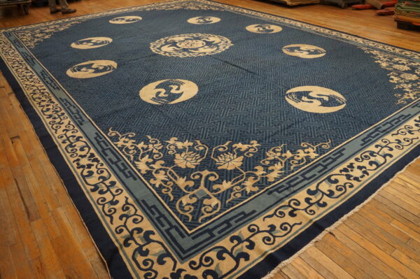 Blue and tan patterned rug with circular medallions and floral borders displayed on a warm-toned wood floor.