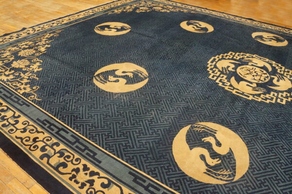 Navy and gold rug featuring large bird roundels and geometric lattice borders on light wood flooring.