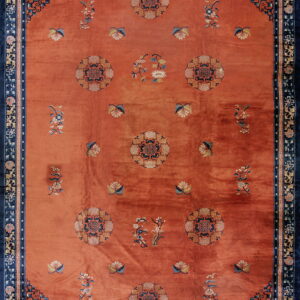 Terracotta rug featuring a navy blue border, circular medallions, and scattered floral designs.