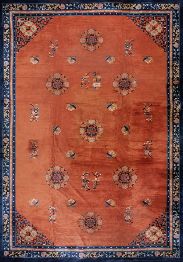 Terracotta rug featuring a navy blue border, circular medallions, and scattered floral designs.