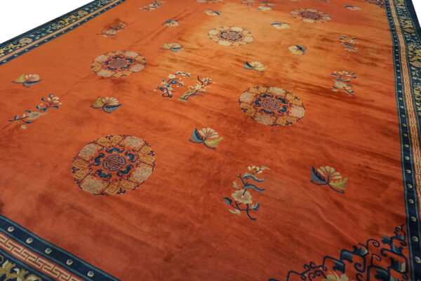 Orange rug with a blue border and repeating circular medallions and scattered floral motifs.
