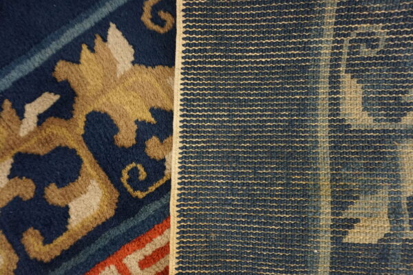 Close-up showing the plush navy and tan patterned rug face next to its tightly woven blue and beige backing.