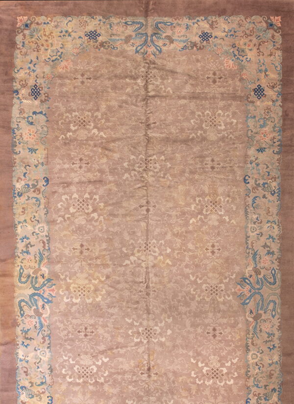 Low-pile dusty rose rug featuring a subtle tonal field and a complex light blue and pink floral border.