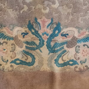Muted low-pile rug detail features teal blue, pink, and tan stylized mirrored animal and floral motifs.