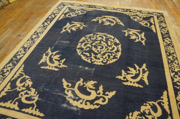 Dark blue rug with a contrasting gold traditional scrolling pattern rests on light wood planks.