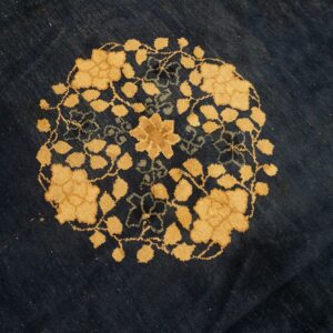 Golden yellow floral medallion and vines detail on a textured, deep navy blue low-pile rug.