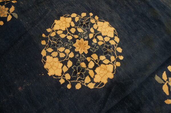 Golden yellow floral medallion and vines detail on a textured, deep navy blue low-pile rug.
