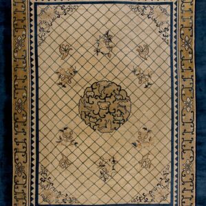 A beige rug features a diamond trellis pattern, a central medallion, and navy blue and gold stylized borders.