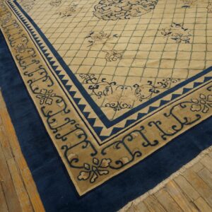 This beige rug features a blue floral lattice pattern and thick navy blue borders over hardwood flooring.