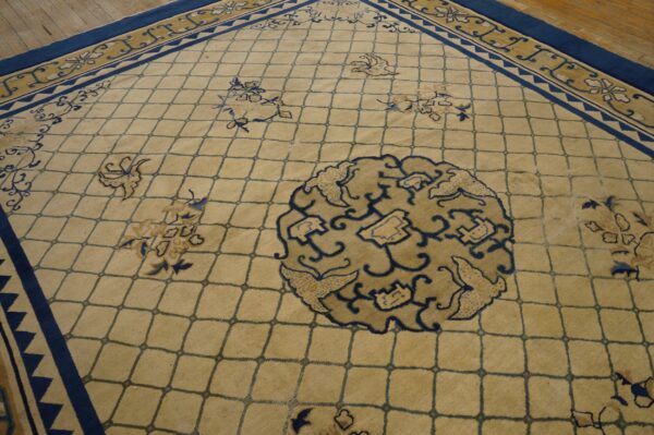 Tan lattice rug featuring blue and tan botanical motifs and thick navy blue borders on wood flooring.