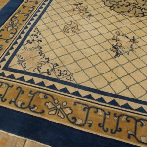Beige rug with blue diamond trellis, framed by wide blue and mustard gold ornate borders on wood floor.