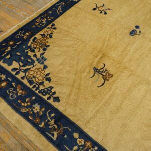 Golden yellow rug with a dark blue floral pattern border rests on rustic exposed wood flooring.