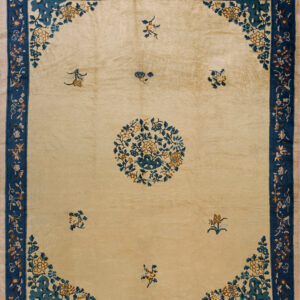 Beige rug featuring a blue and brown floral medallion and spandrels within a wide indigo border.
