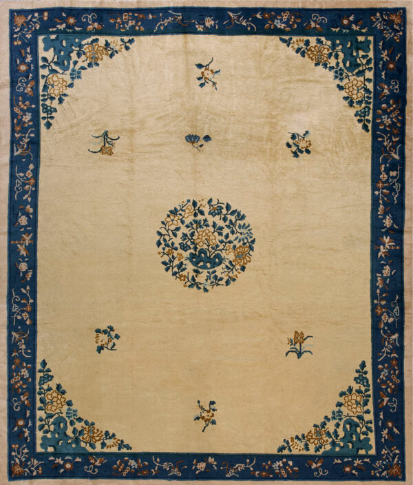 Beige rug featuring a blue and brown floral medallion and spandrels within a wide indigo border.