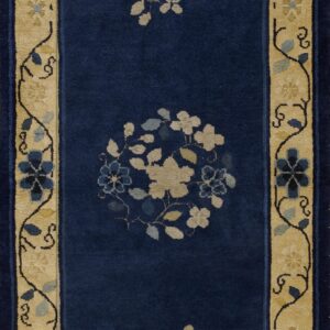 Navy blue runner rug with a wide tan border and scattered beige and blue floral patterns in the field.