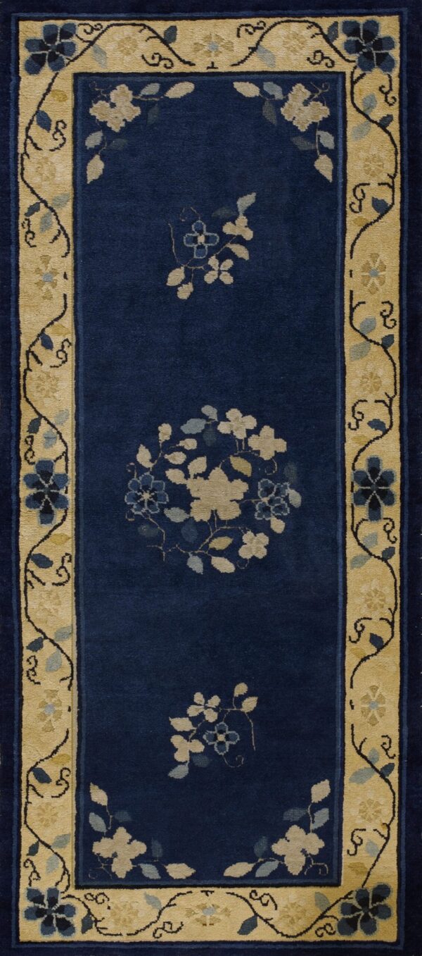 Navy blue runner rug with a wide tan border and scattered beige and blue floral patterns in the field.