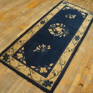 Blue floral runner rug with a wide tan border sits on exposed, light-colored wooden floorboards.