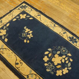 Navy blue runner rug with golden cream floral border sits on light, rustic wood floors.