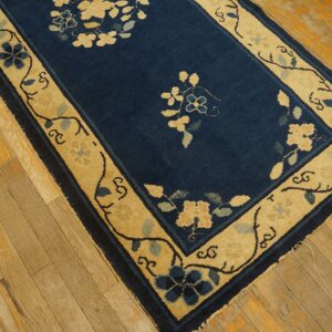 Navy and tan floral runner rug on distressed light brown hardwood floor.