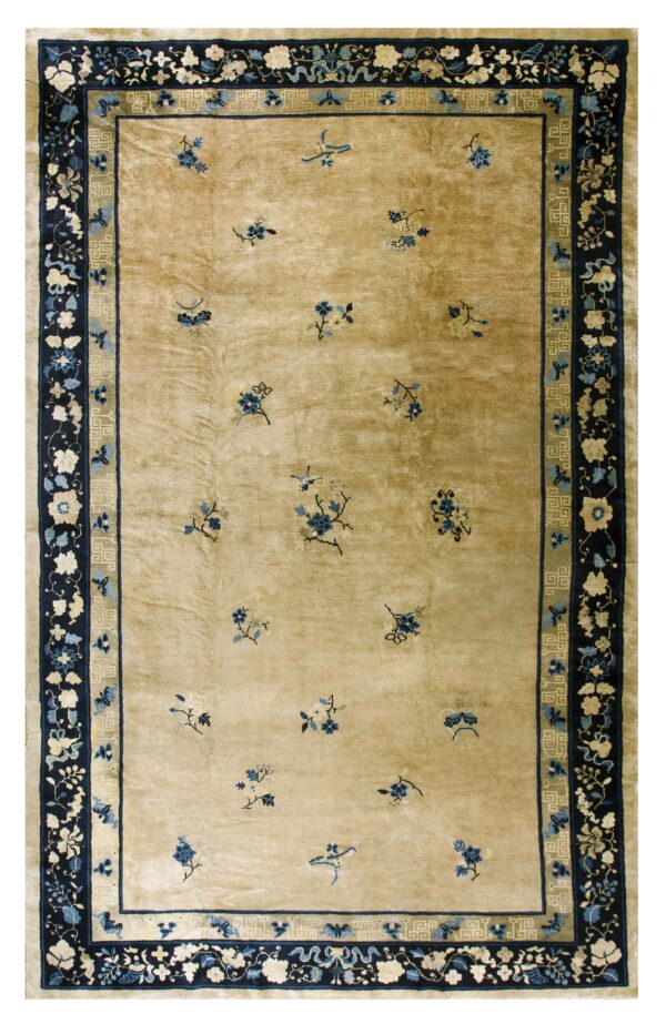 Plush tan rug with scattered blue flowers and elaborate navy borders displaying floral and fret patterns.
