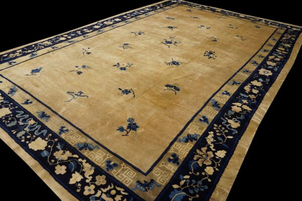 A golden beige rug with sparse blue motifs and complex navy blue floral and geometric borders.