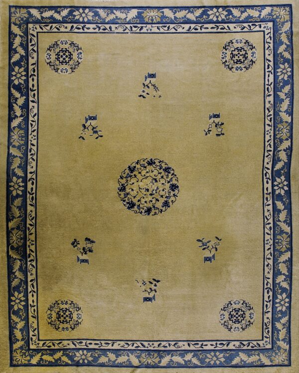 A pale olive rug with a central medallion and scattered motifs, featuring wide indigo blue floral borders.