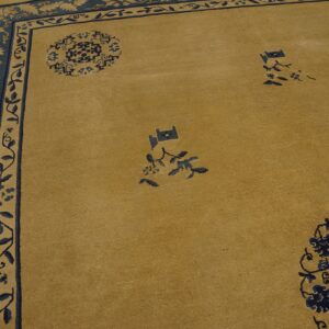 Tan and navy rug features a broad border of contrasting stylized foliage around a low-pile field.