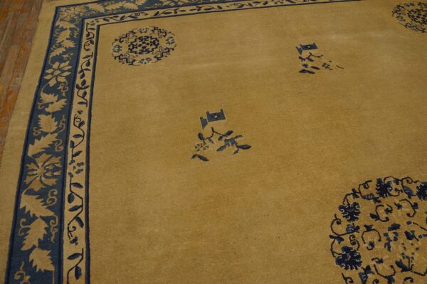 Tan and navy rug features a broad border of contrasting stylized foliage around a low-pile field.