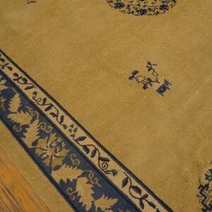 Gold rug with navy geometric and floral motifs, featuring a detailed border on plank wood flooring.