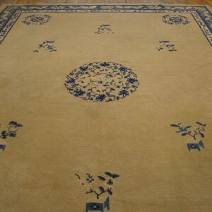 Golden tan rug featuring blue floral medallions and an ornate border on wood floorboards.
