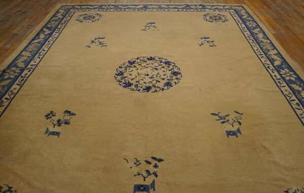 Golden tan rug featuring blue floral medallions and an ornate border on wood floorboards.