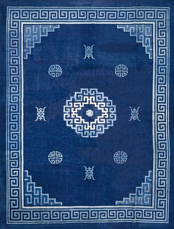 Deep blue rug with geometric light blue greek key border and stylized central and corner motifs.