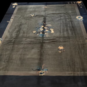 Dark gray rug with high sheen, a navy border, and scattered light blue and gold floral motifs.