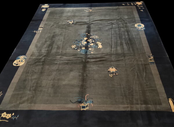 Dark gray rug with high sheen, a navy border, and scattered light blue and gold floral motifs.