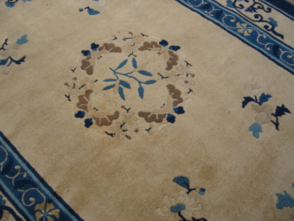 Beige plush rug with sculpted floral patterns in shades of blue, brown, and tan.
