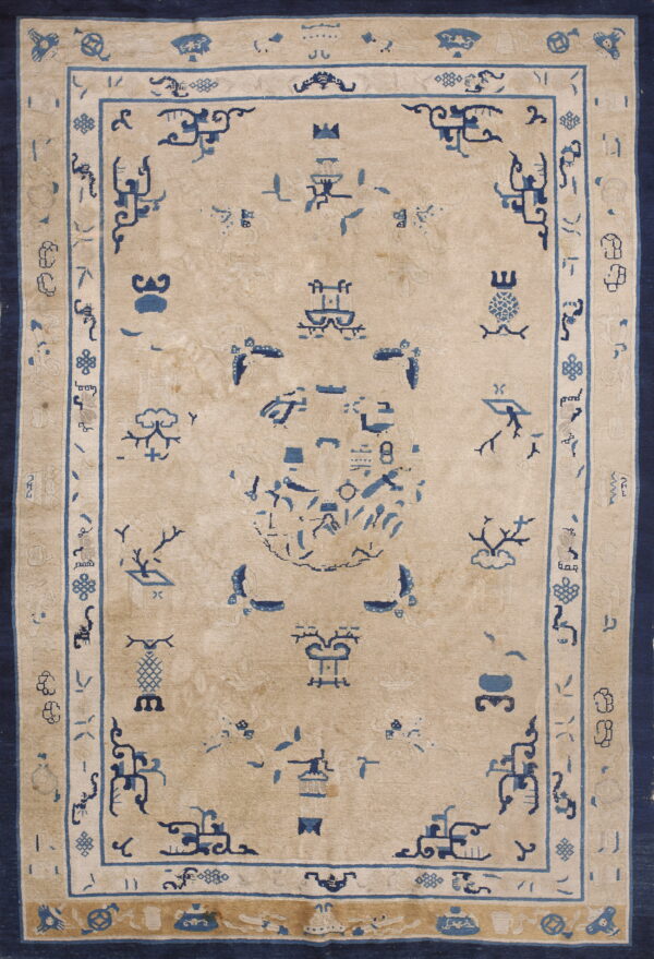Rectangular pale gold rug with detailed dark blue stylized symbols and broad indigo border.