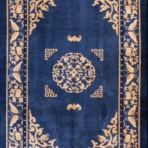 Dark blue rug featuring a bold gold medallion and floral border rests on a light hardwood floor.