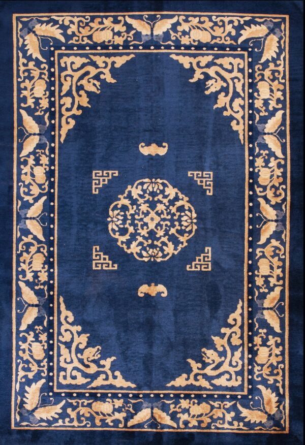 Dark blue rug featuring a bold gold medallion and floral border rests on a light hardwood floor.