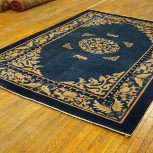A rectangular blue rug with a light gold Asian scroll pattern lies on a shiny wooden floor.