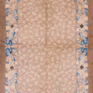 Rectangular low pile rug with a light brown field, mauve border, and colorful floral and bird patterns.