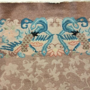 High-pile rug detail showing mirrored blue bird motifs and light floral patterns on a dusty brown field.