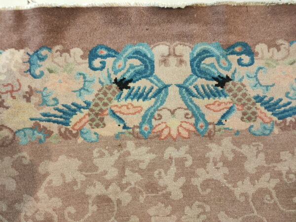 High-pile rug detail showing mirrored blue bird motifs and light floral patterns on a dusty brown field.