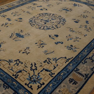 Light tan rug featuring deep blue, stylized floral patterns and multiple wide borders on wood plank flooring.
