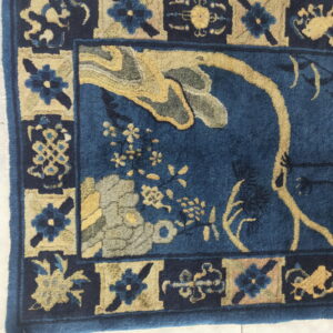 High-pile blue rug featuring yellow and gray floral patterns within a bordered design shown on white tile.