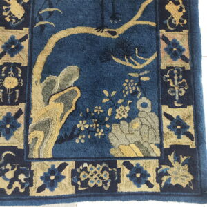 Blue high-pile rug with stylized gold and gray tree motifs and a detailed floral panel border.