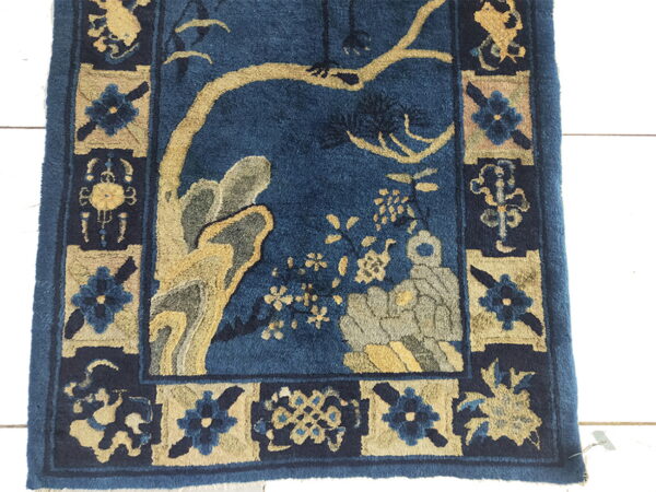 Blue high-pile rug with stylized gold and gray tree motifs and a detailed floral panel border.