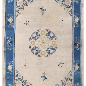 Off-white area rug with a wide blue border and detailed blue and cream-colored floral designs.